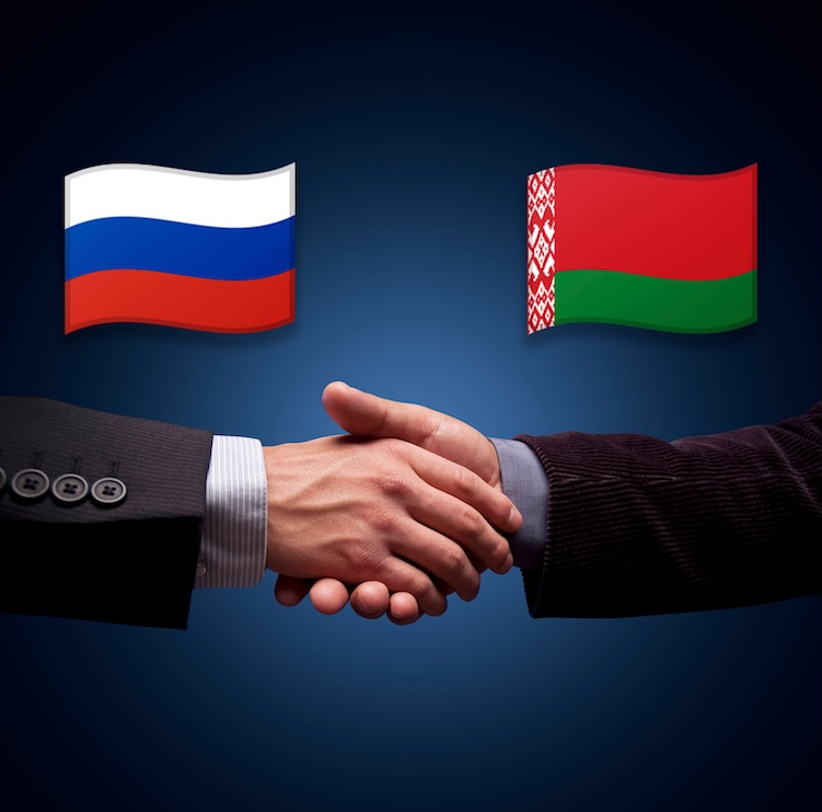 Twee mannenhanden die elkaar de hand schudden met vlaggetjes van Rusland en Belarus