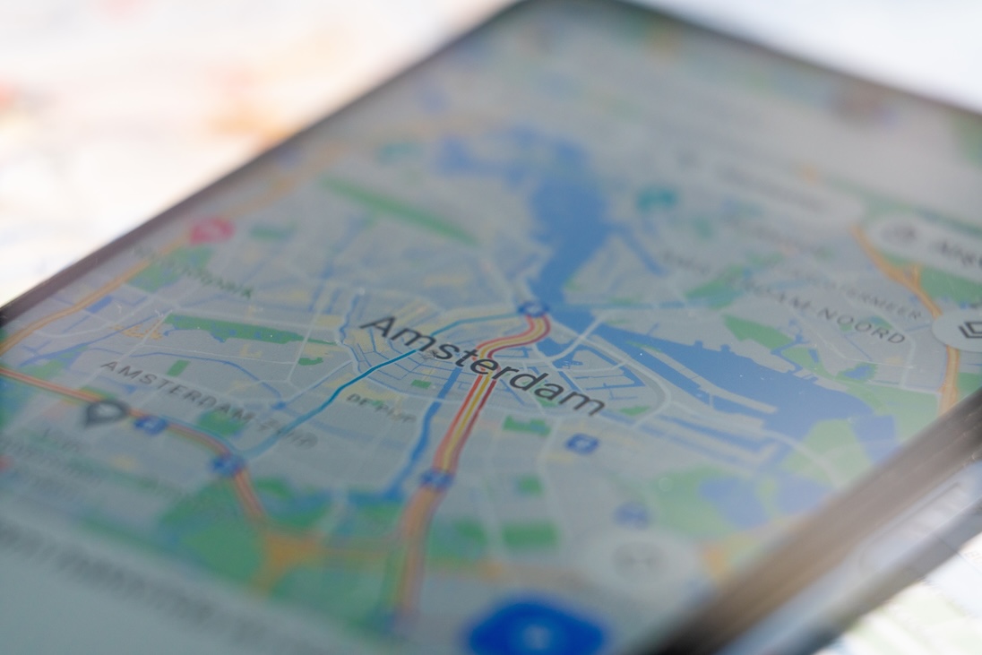 Smartphone met daarop google maps met in centrum daarvan Amsterdam