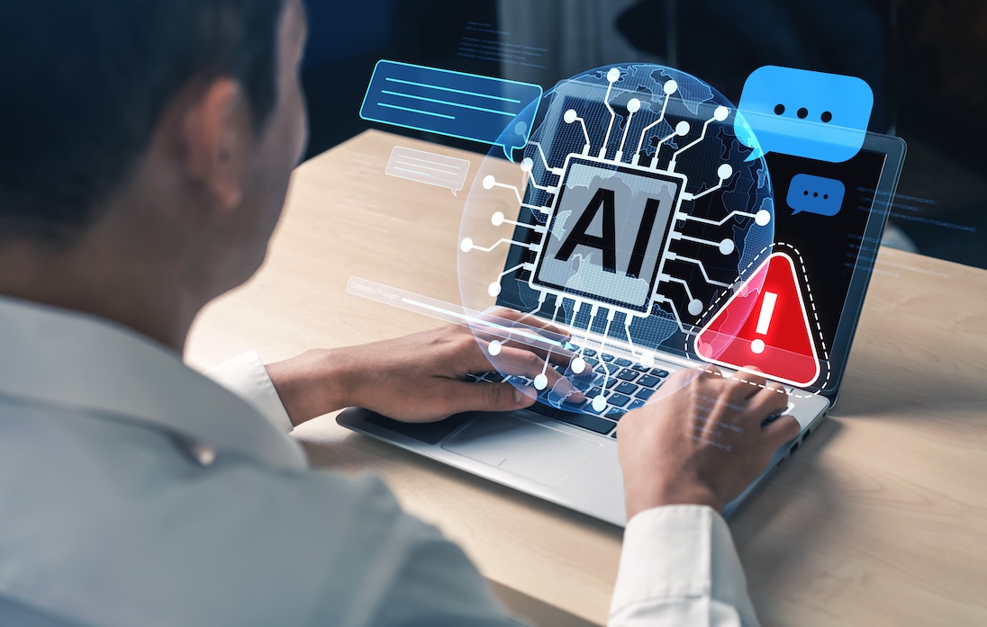 Man kijkt naar scherm van laptop, waaruit AI en waarschuwingsteken naar voren komt